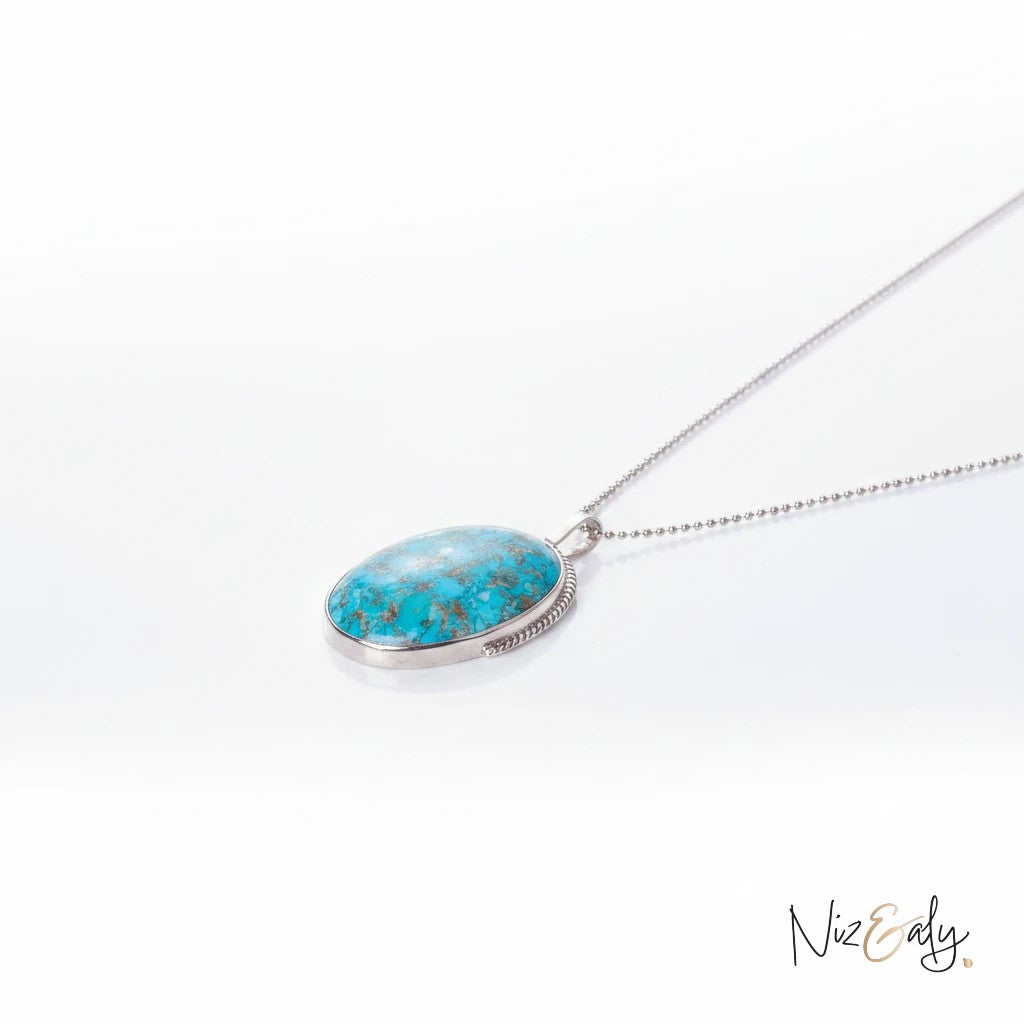 Niz & Aly oval turquoise pendant necklace with pyrite accents on a delicate silver chain against a white background.