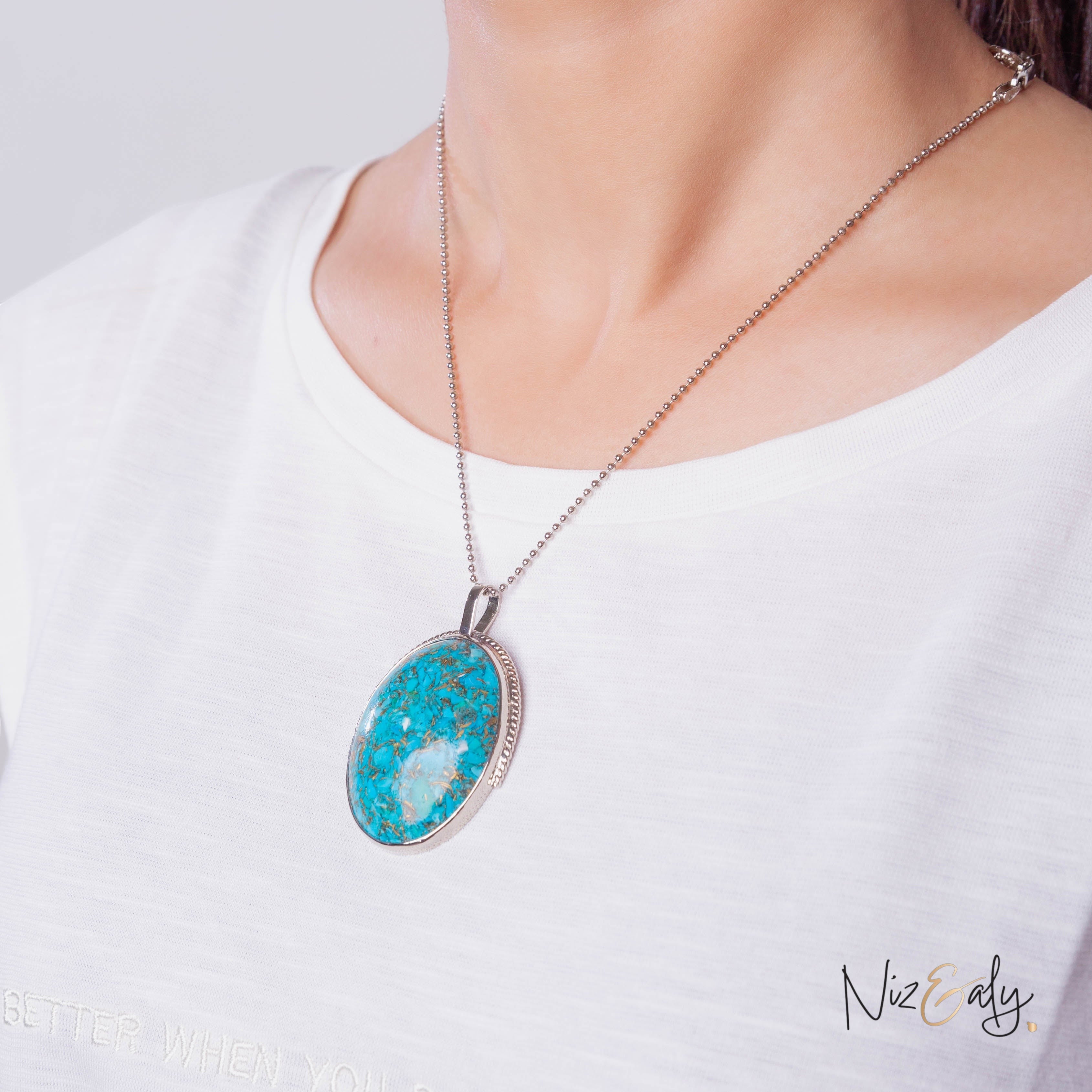 Niz & Aly turquoise pendant necklace with pyrite accents on a silver ball chain worn against a white shirt
