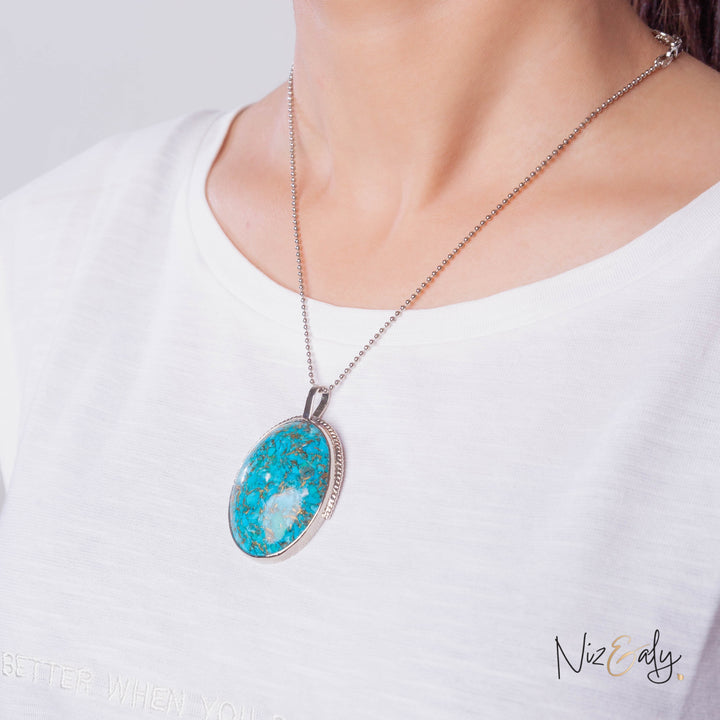 Niz & Aly turquoise pendant necklace with pyrite accents on a silver ball chain worn against a white shirt