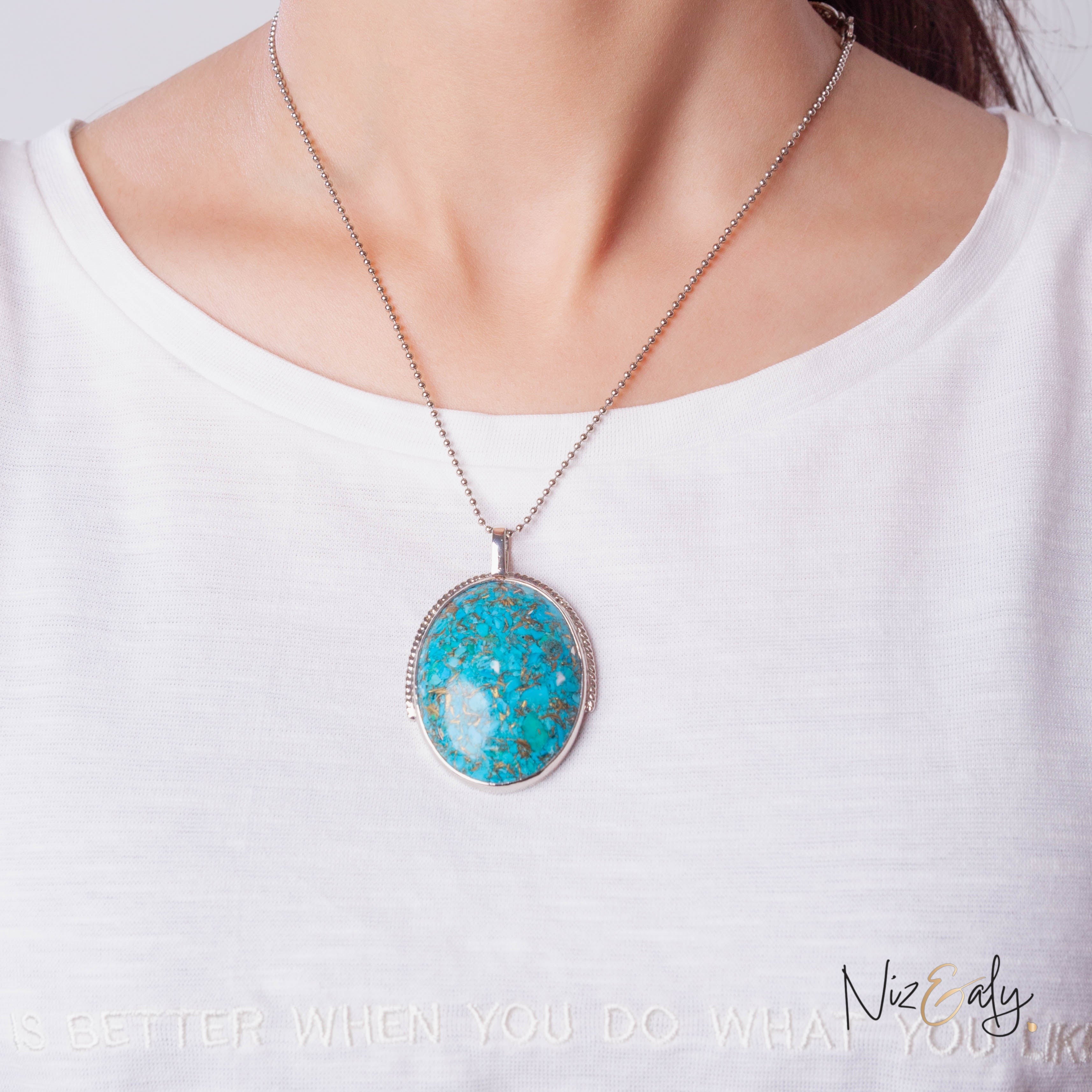 Niz & Aly turquoise pendant necklace with natural pyrite accents on a silver ball chain worn against a white shirt.