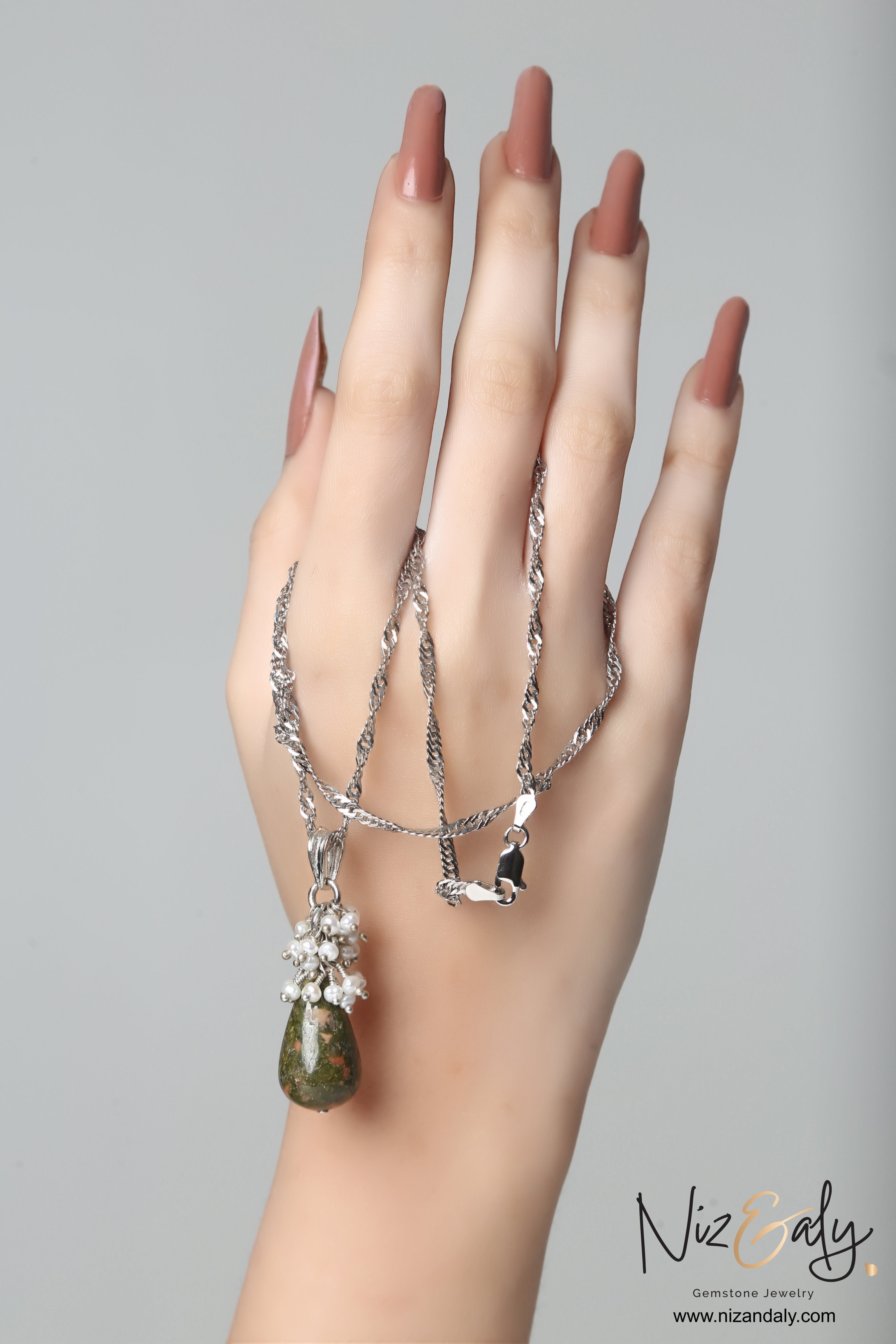 Niz & Aly unakite jasper and freshwater pearl drop pendant necklace on a silver chain held by a hand