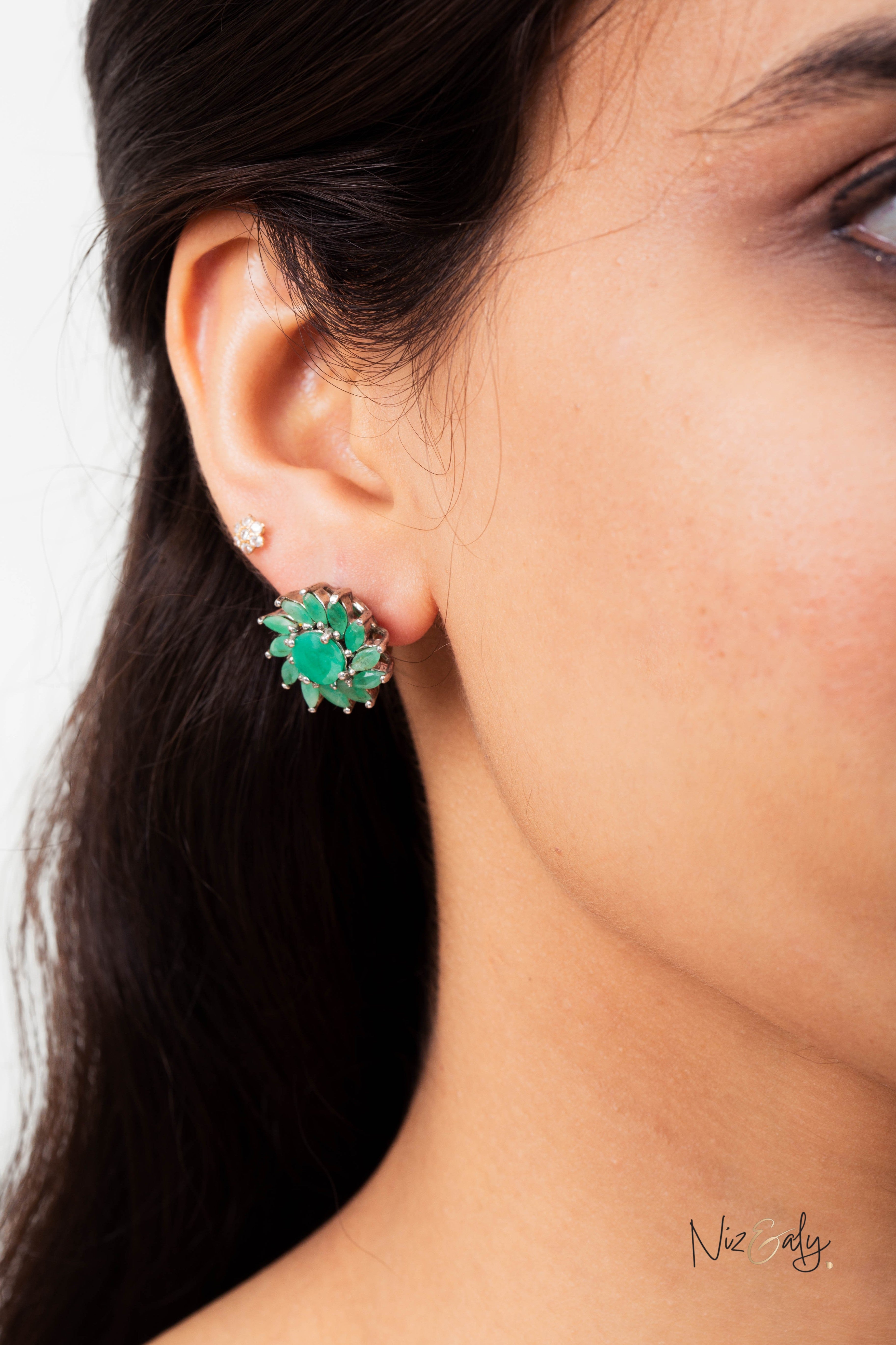 Niz & Aly vintage-style stud earrings featuring a cluster of natural green emeralds worn on a model's ear