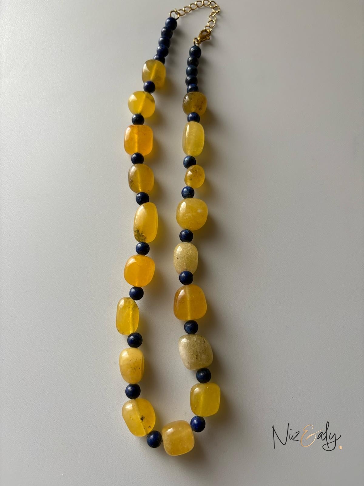 Niz & Aly necklace featuring alternating yellow agate and deep blue lapis lazuli gemstone beads on a gold-tone chain.
