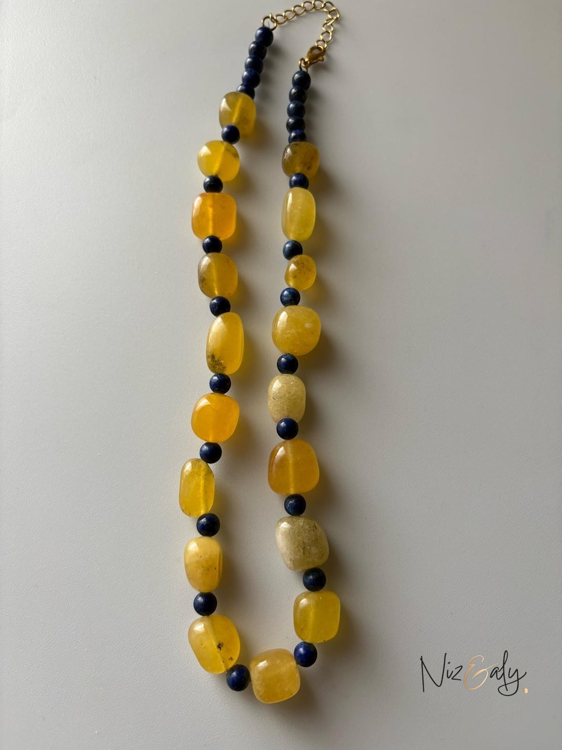 Niz & Aly necklace featuring alternating yellow agate and deep blue lapis lazuli gemstone beads on a gold-tone chain.
