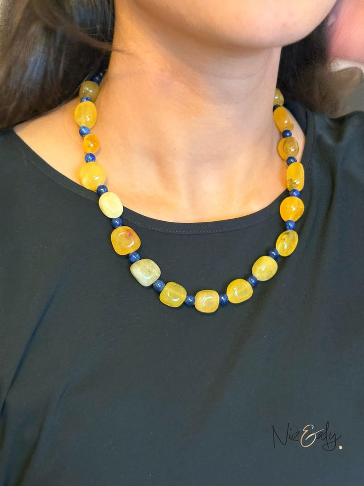 Niz & Aly necklace featuring polished yellow agate and deep blue lapis lazuli beads worn on a black top