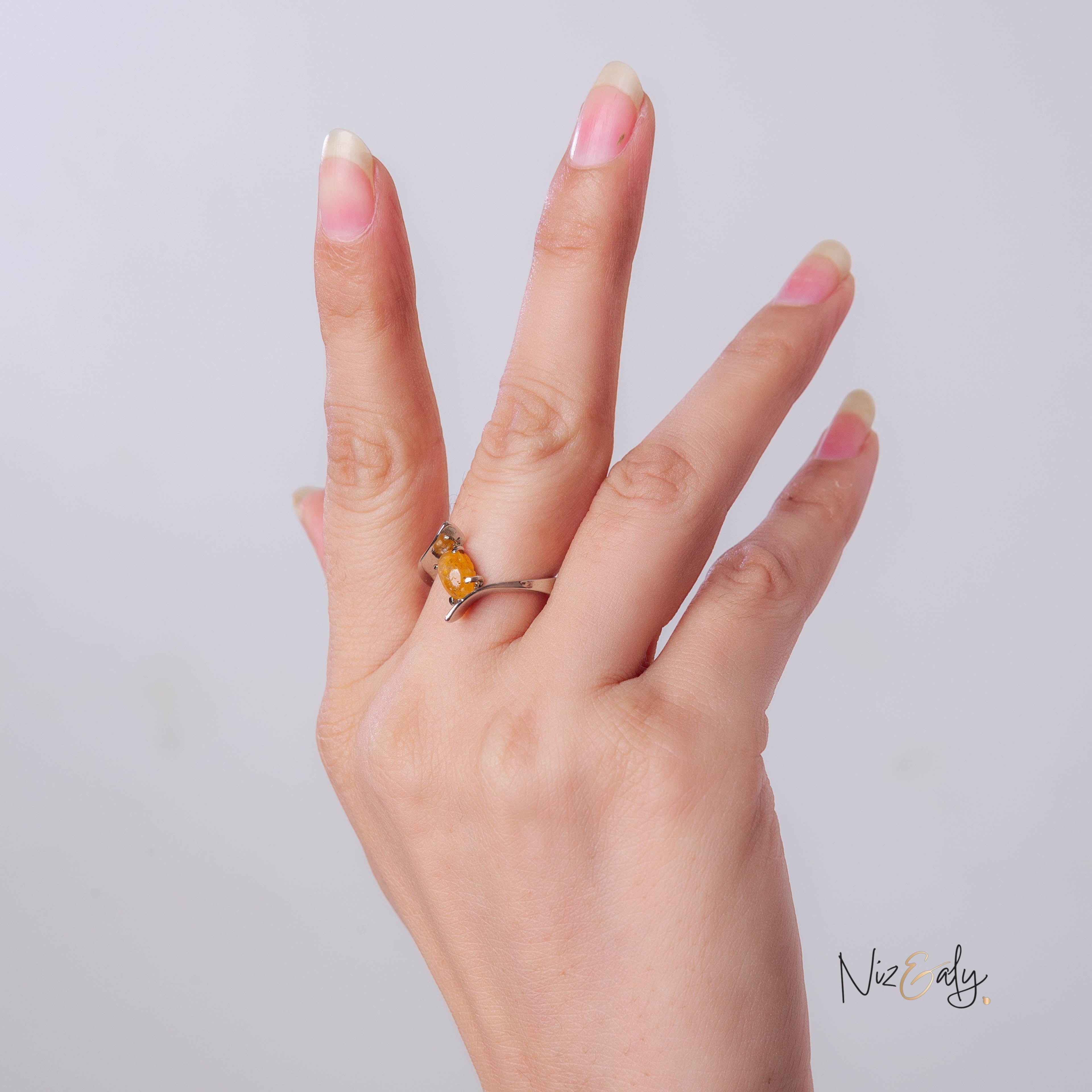 Niz & Aly yellow citrine gemstone ring with an adjustable silver-tone open-bypass band worn on a woman's finger.