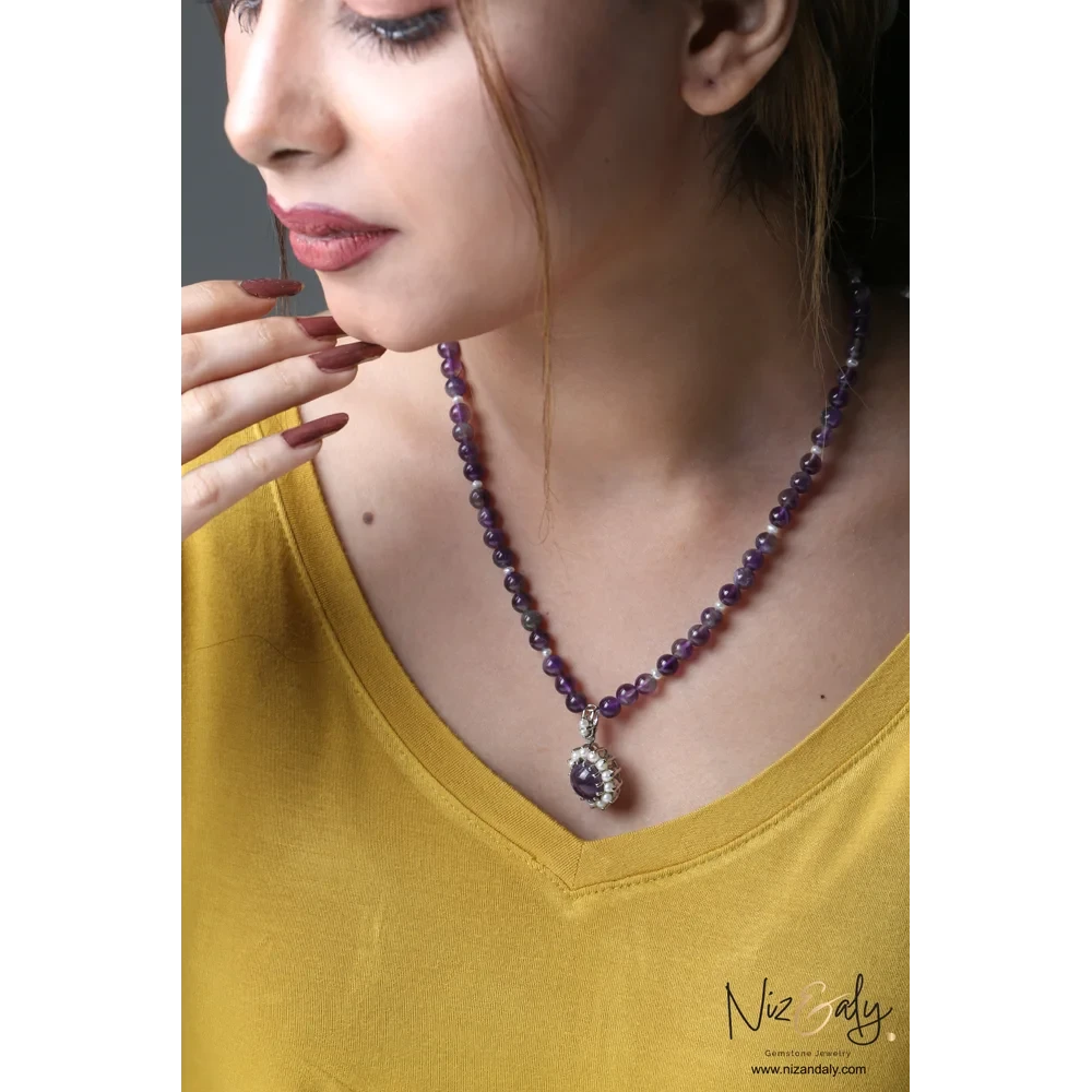 Niz & Aly amethyst and pearl pendant necklace on a beaded amethyst strand worn by a woman in a yellow top