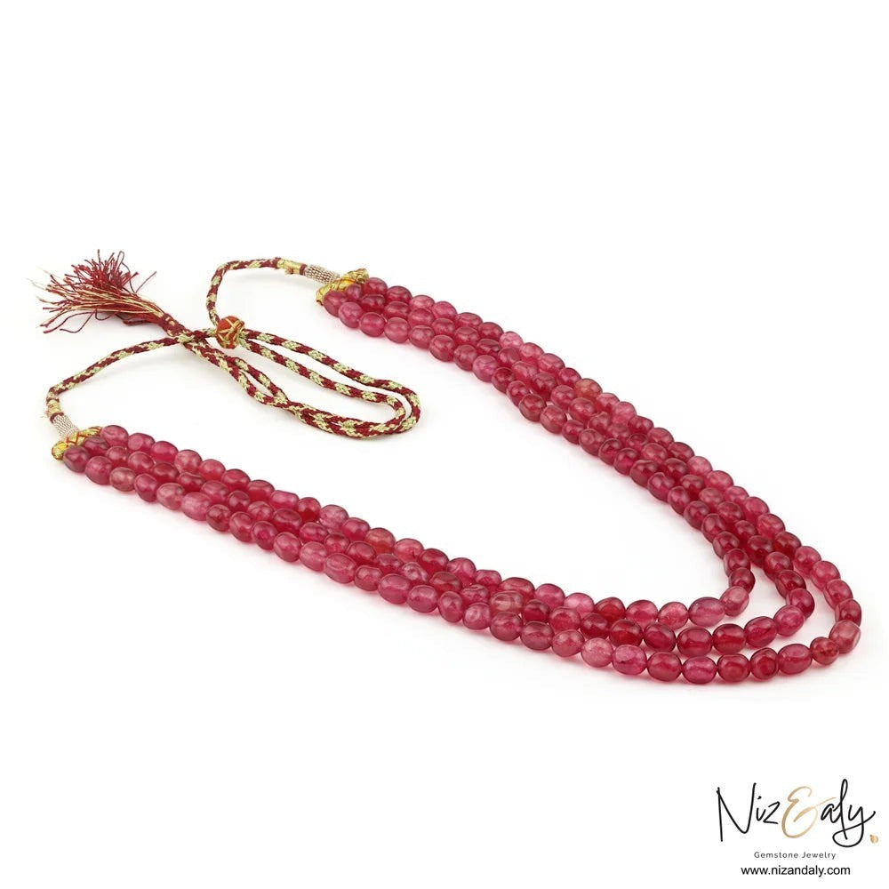 Niz & Aly triple strand cherry quartz beaded necklace with a decorative rope-style tassel closure.