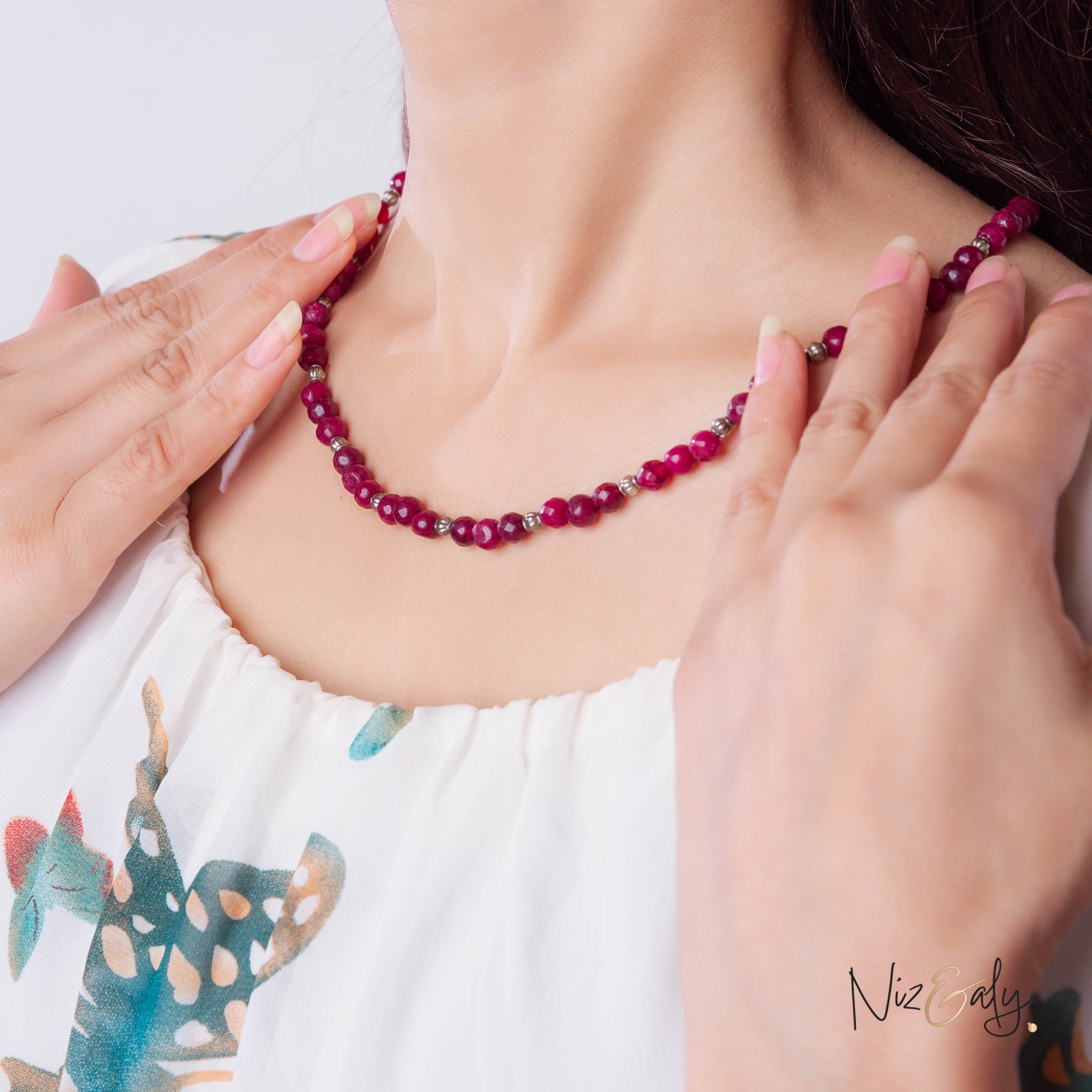 Niz & Aly faceted almandine garnet bead necklace worn by a woman in a white floral top