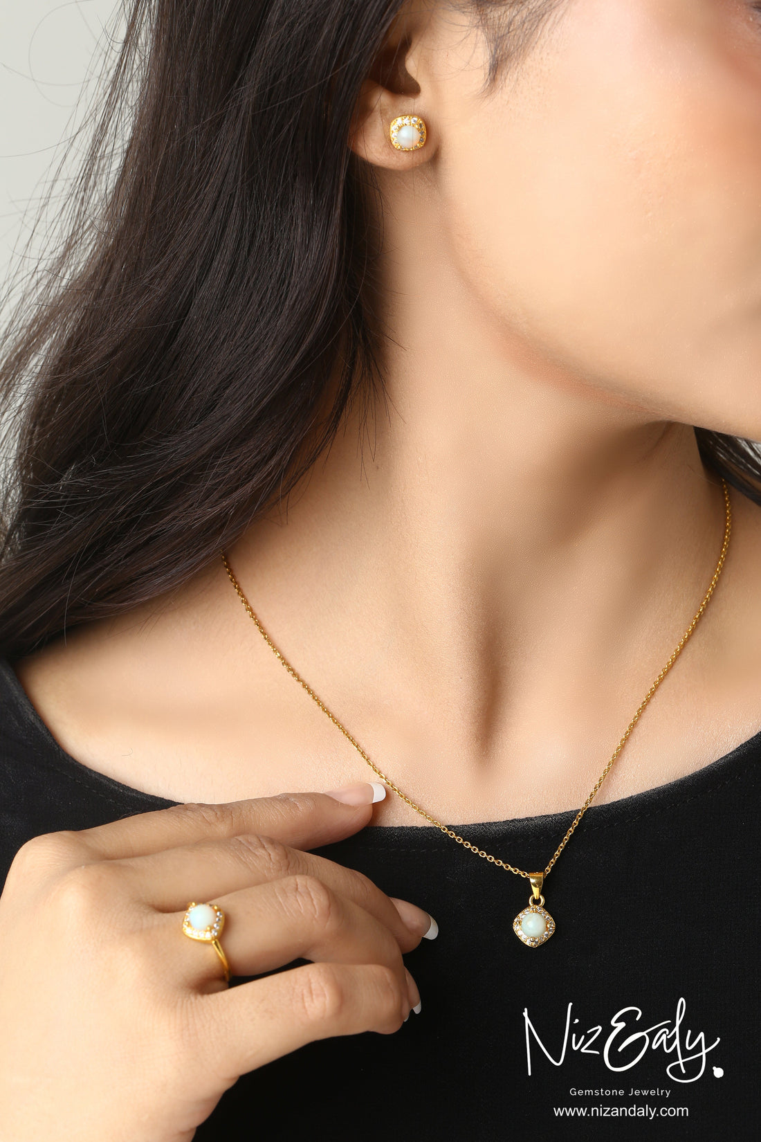 Niz & Aly gold-plated opal jewelry set featuring a pendant necklace, ring, and stud earrings on a woman