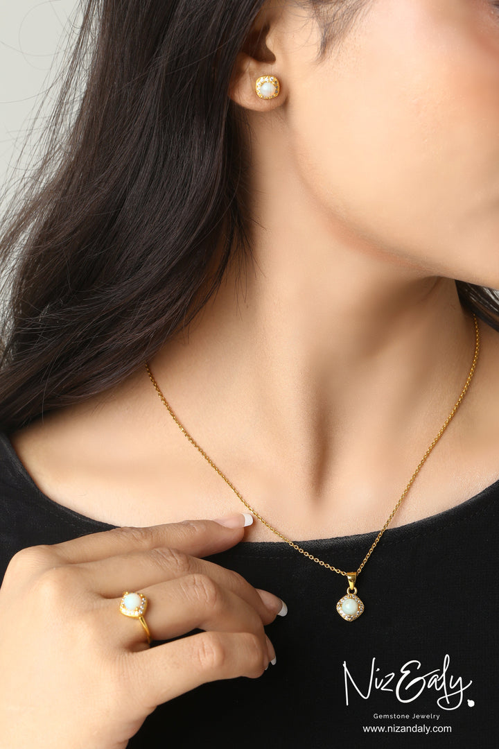 Niz & Aly gold-plated opal jewelry set featuring a pendant necklace, ring, and stud earrings on a woman