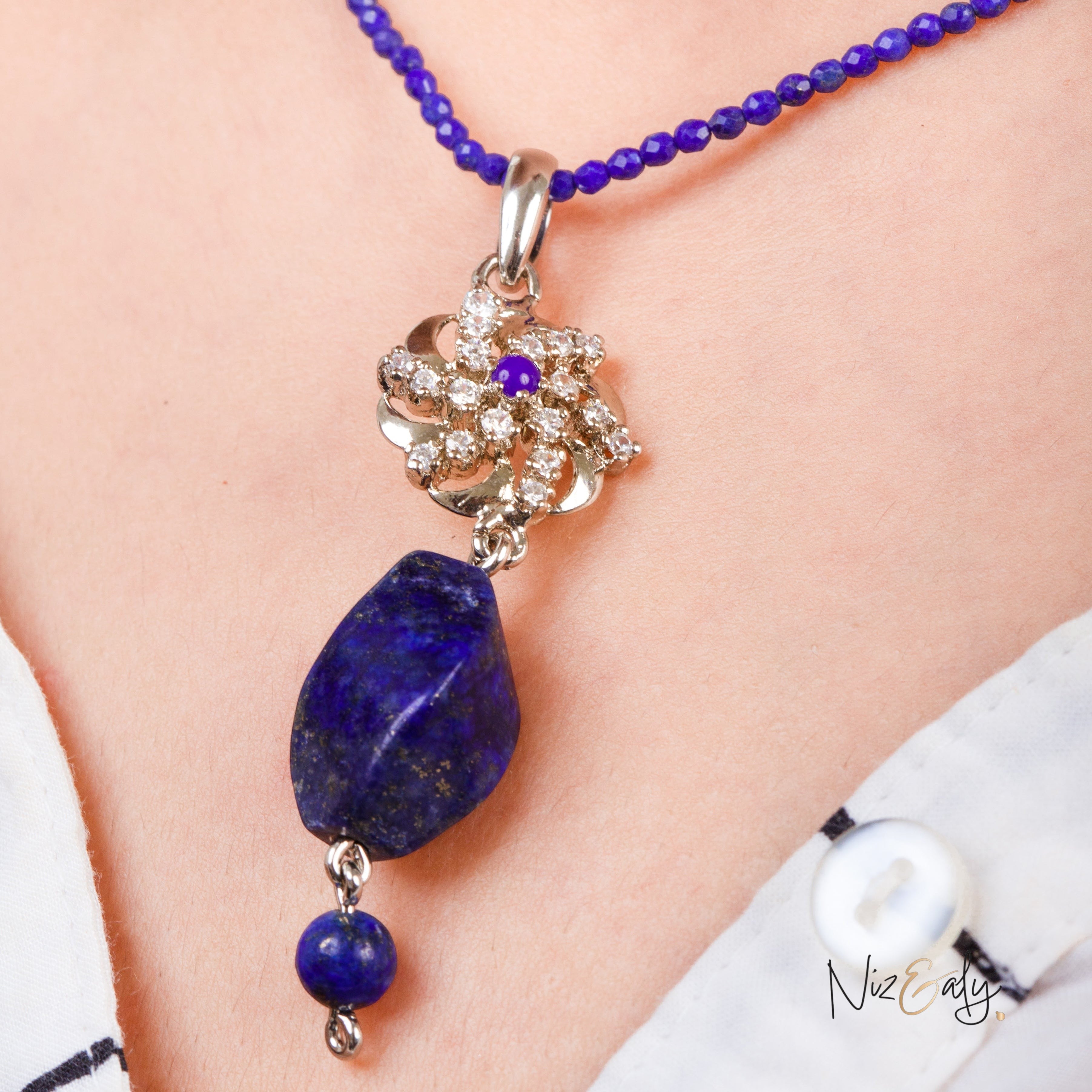 Niz & Aly lapis locket featuring a raw blue stone pendant with a floral diamond accent on a faceted lapis bead chain.