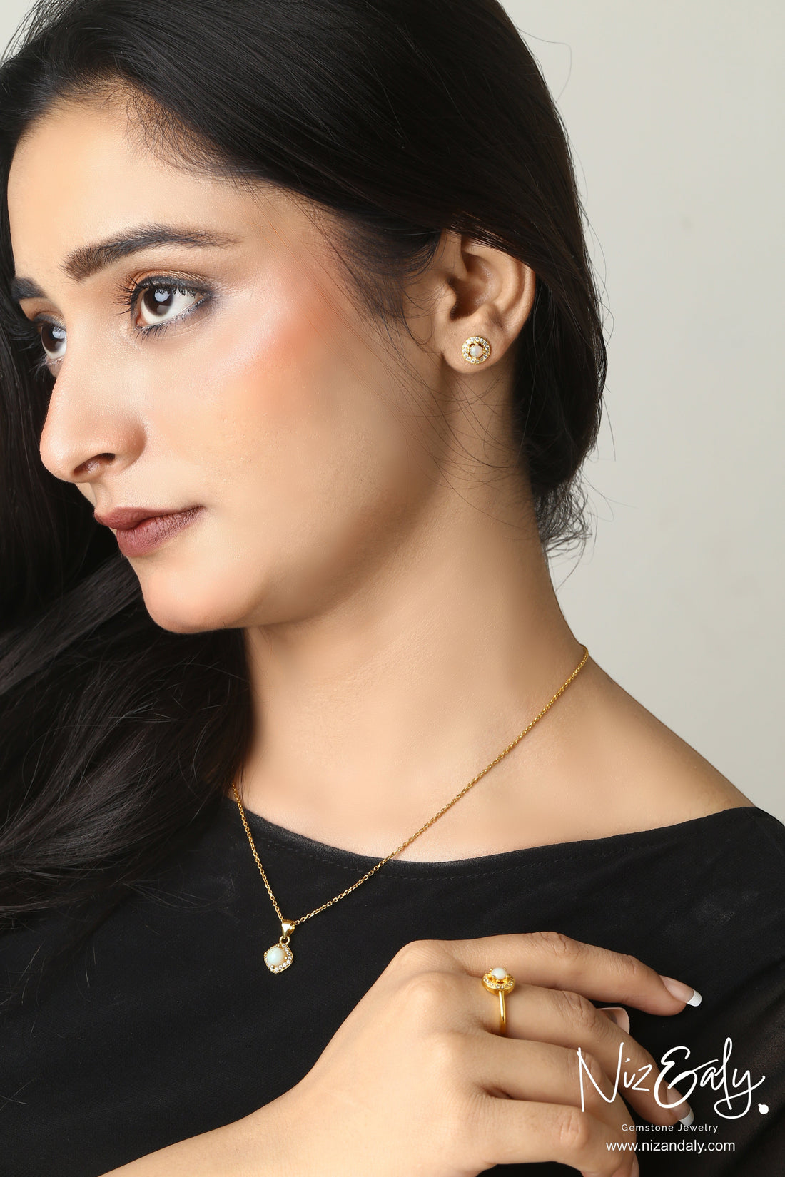 Niz & Aly Opalea jewelry set featuring a round white Australian opal pendant, stud earrings, and ring on a model.
